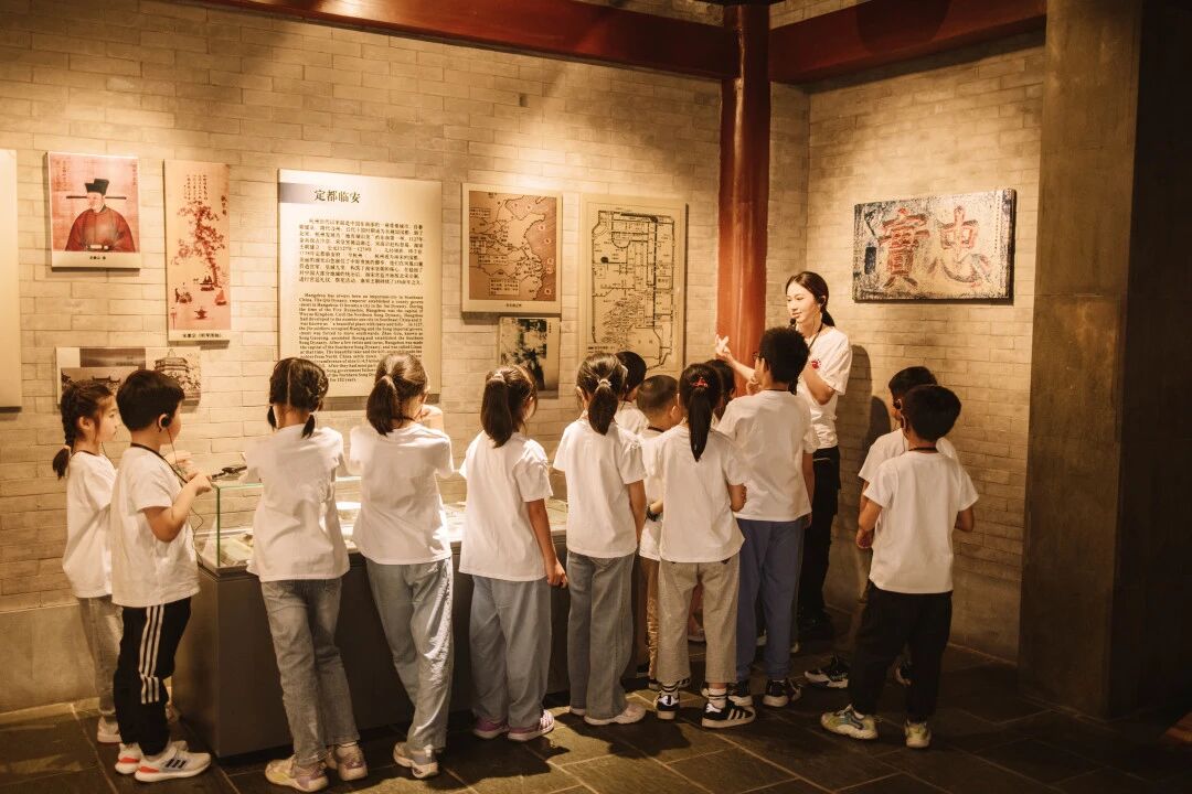 身穿白衣的学生在博物馆内跟随老师参观展览，浸思研学博物馆课堂实拍