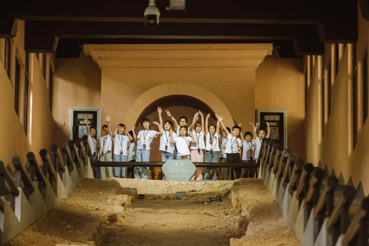 学生在考古发掘现场的探方内兴奋合影留念，浸思研学考古体验活动实拍