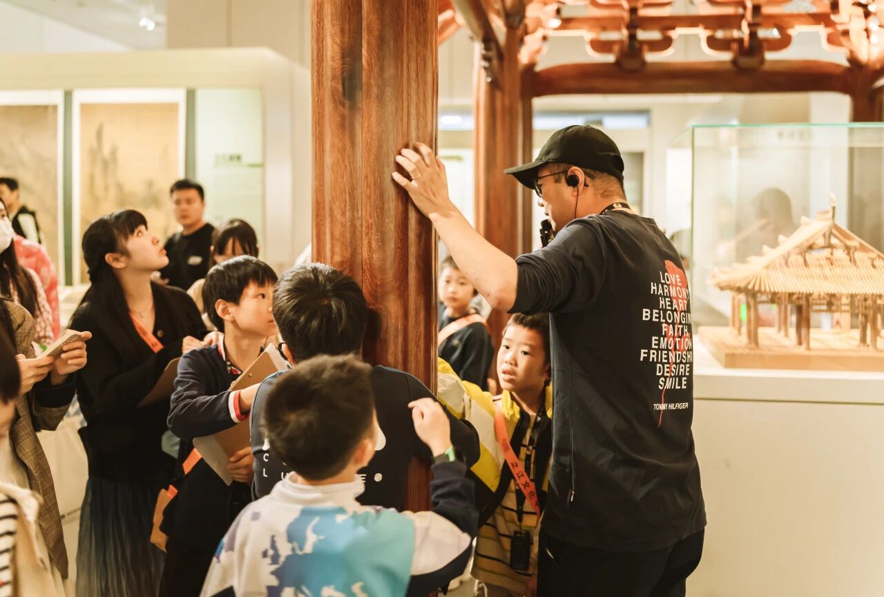 导游在博物馆内带小朋友触摸观察巨大木柱，浸思研学沉浸式教学实拍