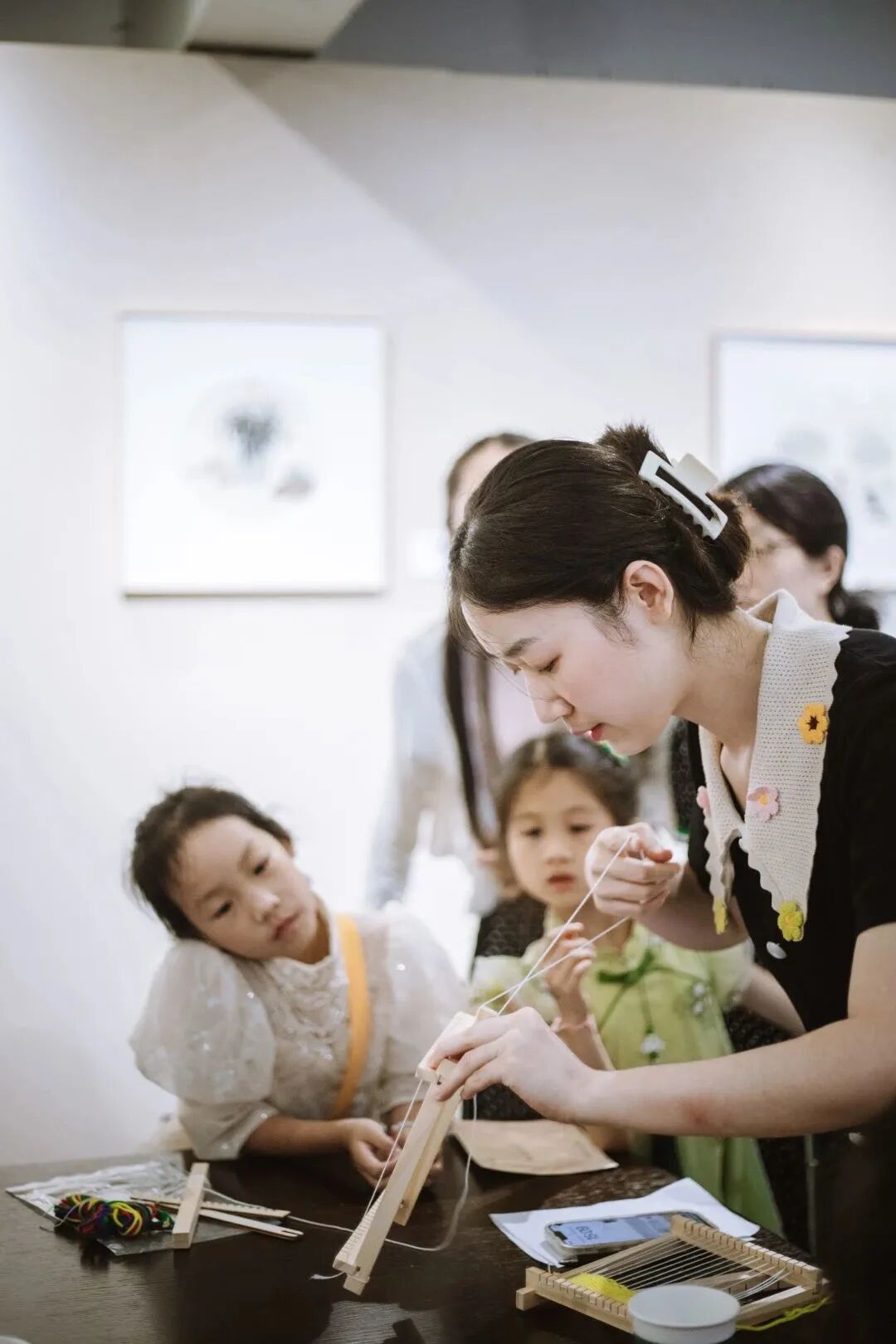 年轻女性教两名小女孩进行手工编织，浸思研学非遗手作实拍