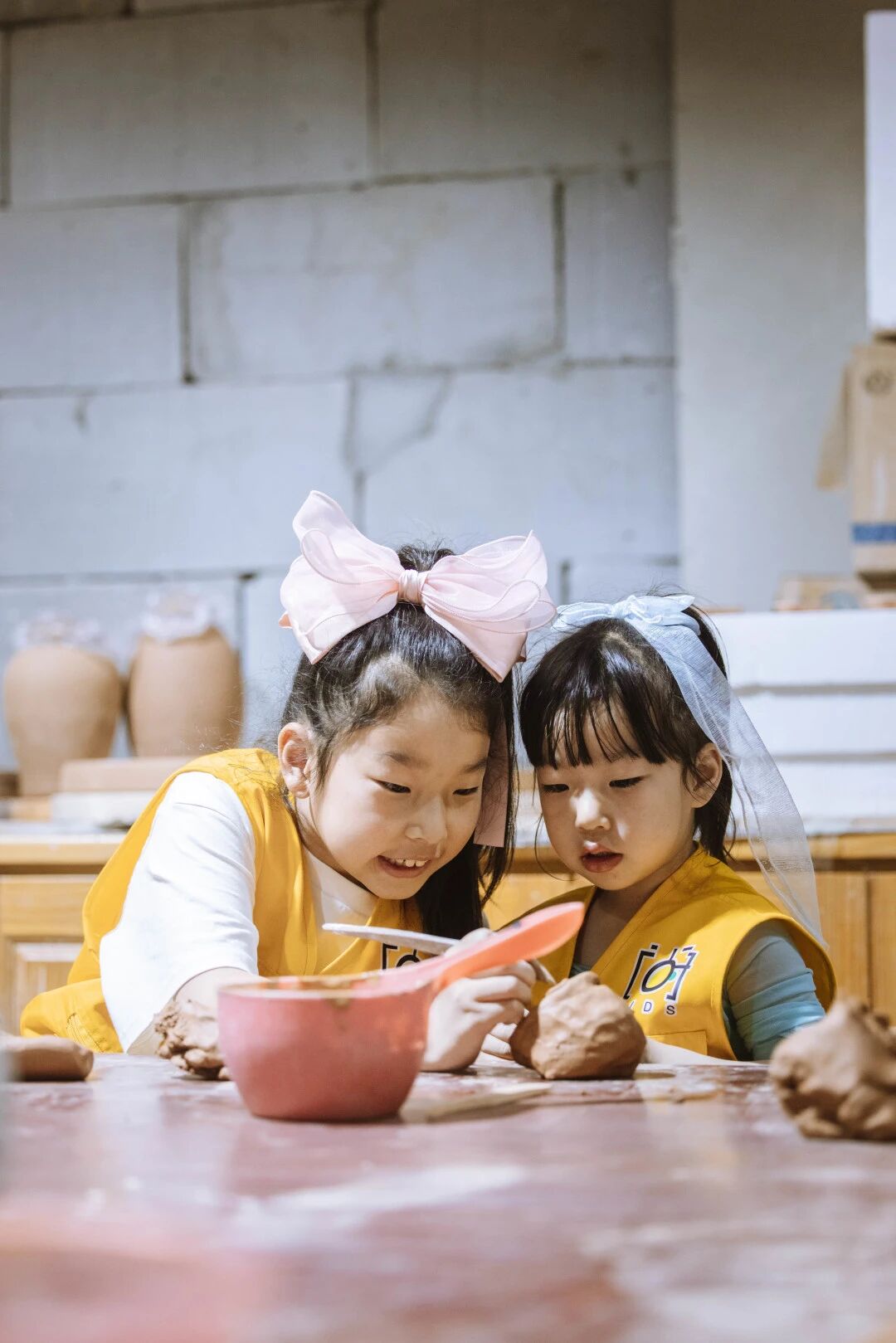 穿黄色围裙的小女孩在陶艺教室专心玩泥巴，浸思研学陶艺体验实拍