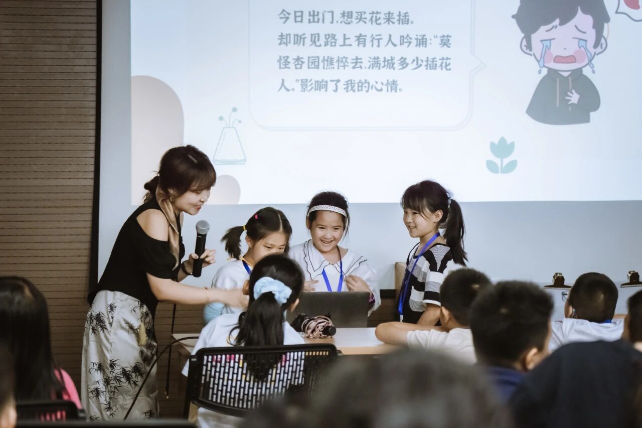 女老师给小学生讲解投影幕布上的古诗内容，浸思研学诗词课堂实拍