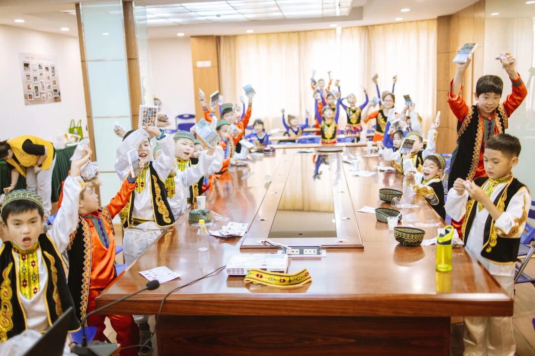 穿民族服装的孩子在会议室兴奋举手欢呼，浸思研学互动课堂实拍