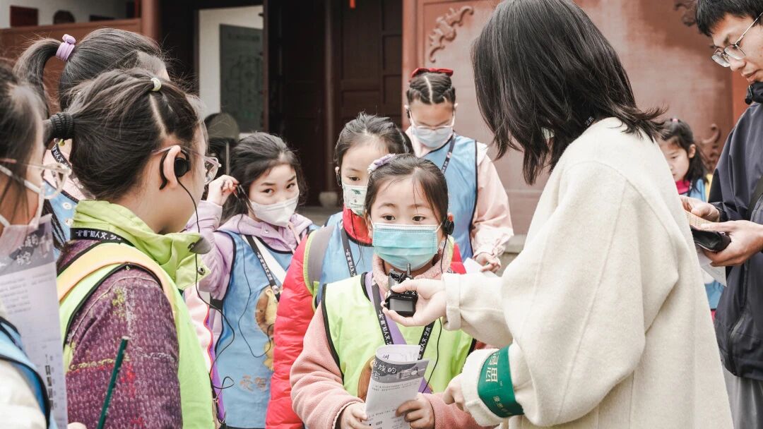戴口罩的小学生在古建筑前排队等待，浸思研学户外研学实拍